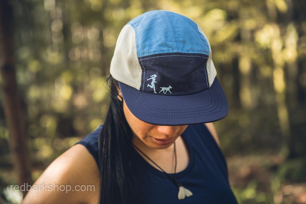 Woman wearing sky blue and navy running hat with dog