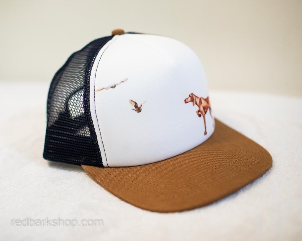 Side detail of flying grouse on bird dog hat with pointing vizsla