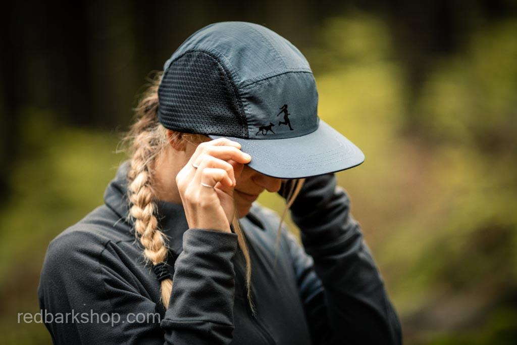 blonde woman wearing black and grey running hat with dog and girl details