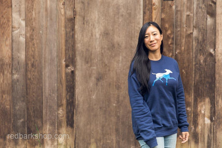 Asian woman smiling wearing a squamish mountain dog sweatshirt in navy
